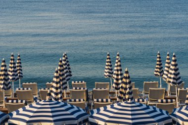 Şemsiyeler ve güneşlikler Fransa 'nın güneyinde Nice sahilinde bir yaz sabahı.