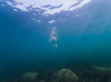 Su altı fotoğrafı, bir kız tek başına denizde derinlerde yüzer, gündüzleri okyanusta.. 