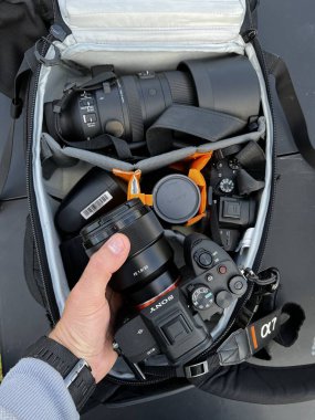 Estonia, Tallinn August 25, 2024. A man's hand takes out a Sony alpha mark 4 camera from a photo backpack with lenses and a spare mirrorless camera. Illustrative editorial.  clipart