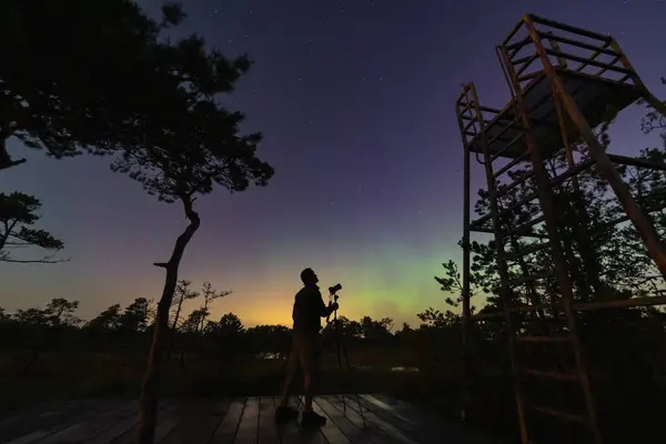 Bir peyzaj astrofotografçısı gece vakti kuzey ışıkları sırasında Seli bataklığında kamerayla fotoğraf çeker..