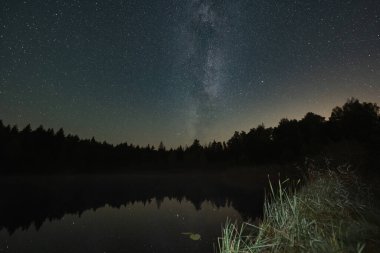 Peyzaj astrofotografı, yıldızlı gökyüzü ve Vahessaare Gölü üzerindeki Samanyolu Eylül ayında Estonya 'da.