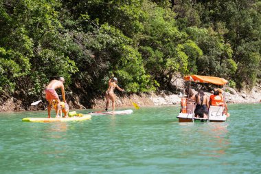 Fransa, Verdon, 10 Temmuz 2024. İnsanlar sıcak bir yaz gününde Verdon Nehri 'nde su katamaranı ve köpek kürek tahtasında yelken açarlar..