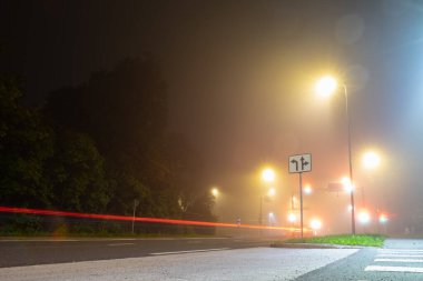 Tallinn 'de sonbaharda gece sisli kavşaklar ve araba stop lambaları.