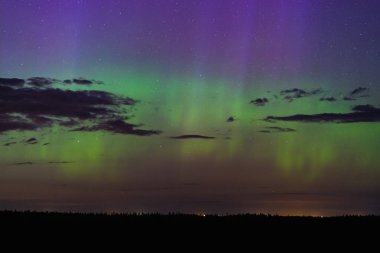 Gece yıldızlı gökyüzü, bulutlar ve doğa fenomeni kuzey ışıkları. Ağustos 'ta Estonya doğası. Telefoto lens görüntüsü.