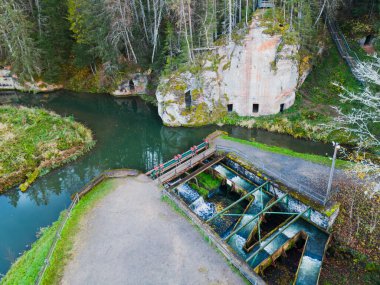 Fish ladder and sandstone caves on the Ligatne River, a tributary of the Gauja in Latvia. Photo taken on an autumn evening, drone point of view view. clipart