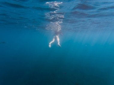Genç kız mavi okyanusta tek başına yüzüyor derinlerde, sualtı fotoğrafı aksiyon kamerasında..