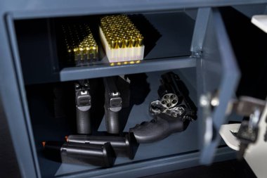 Pistols, revolver and cartridges in a gun safe, close-up photo. clipart