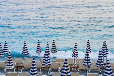 Fransa 'nın güneyinde Nice' de bir yaz sabahı erken saatlerde katlanmış şemsiyeler ve boş güneşlikler. Gök mavisi. 