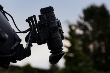 Night vision monocular mounted on a helmet, photo against the sky.