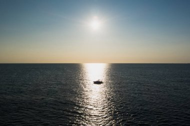 Baltık Denizi 'nde bir yaz akşamı gün batımında küçük bir teknenin silueti, insansız hava aracının fotoğraf görüntüsü..