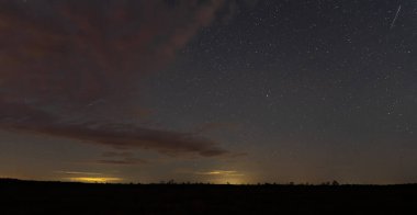 Gece sahnesi, Estonya doğası. Kara toprak ve ağaçlar, yıldızlı gökyüzü ve bulutlar.
