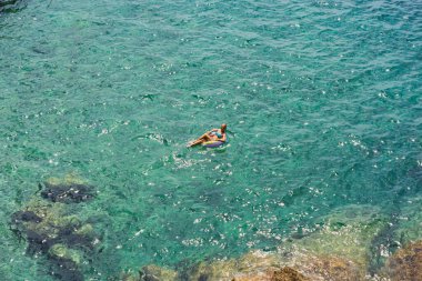 Şişme yüzüklü bir kadın yaz günü Azure Denizi 'nde yüzer. Cote DAzur.