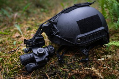  Ballistic helmet with night vision monocular lies on the ground. clipart