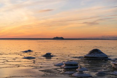 Kış deniz manzarası. Donmuş Baltık Denizi ve gün batımında bir feribot..