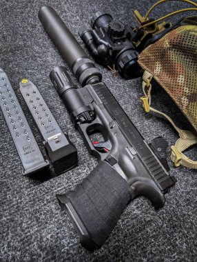 Baltık 10 Aralık 2024. Taktik silah, susturuculu Glock 19 tabanca, el feneri, kırmızı nokta görüşü ve gece görüş cihazı. Dikey fotoğraf.