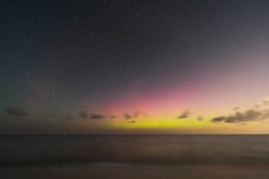Sakin bir okyanusun üzerinde dans eden Aurora Borealis 'in nefes kesici görüntüsü. Aurora Borealis 'in canlı renkleri gece gökyüzünü aydınlatarak büyüleyici bir manzara yaratıyor. Huzurlu okyanus göksel görüntüyü yansıtıyor, ruhani güzelliğe ekliyor.