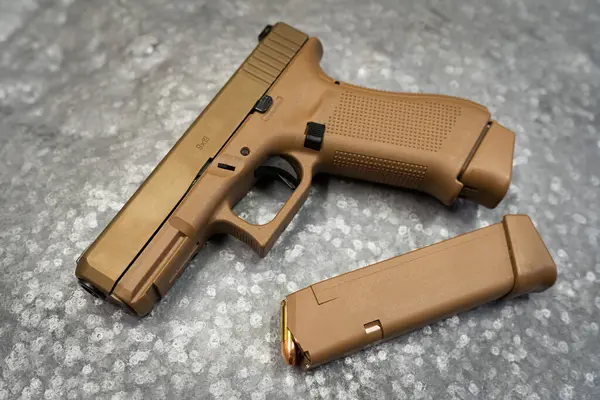 Atış poligonundaki metal bir hedefe çakal renginde taktik tabanca. Fotoğrafı kapat..