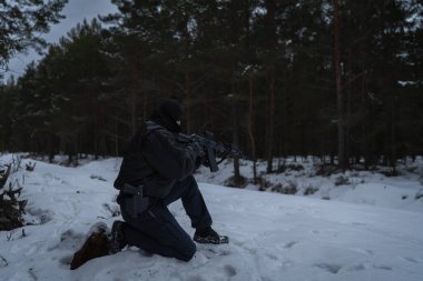 Bir sınır muhafızı özel kuvvetler askeri, alacakaranlık ormanlarında kırmızı noktalı tüfekle nişan alıyor..