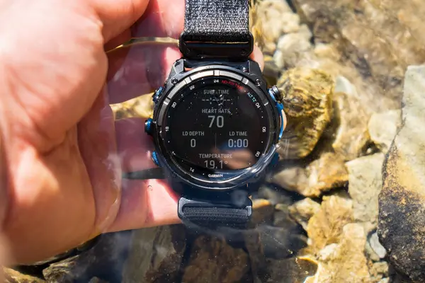 Estonya, Rummu 25 Mayıs 2024 dalış bilgisayarı akıllı Garmin 'in gölde bir adamın elinde Mk3i' yi inişini izliyor..