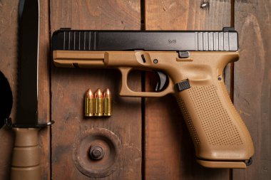 Taktik kamuflaj tabancası 9x19mm, ordu bıçağı ve tahta yüzeyde fişekler..
