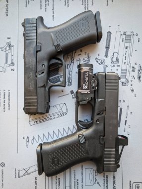 Baltık 16 Ocak 2025. İki modern Glock 43x tabanca, kolatör görüşlü ve el fenerli. Resimli editör, dikey fotoğraf.