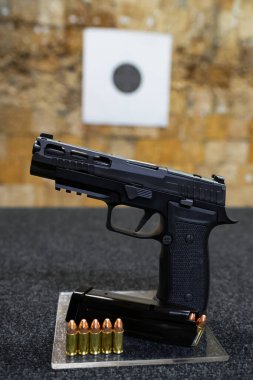 Atış poligonunda yuvaları olan taktik modern 9mm tabanca. Dikey fotoğraf.