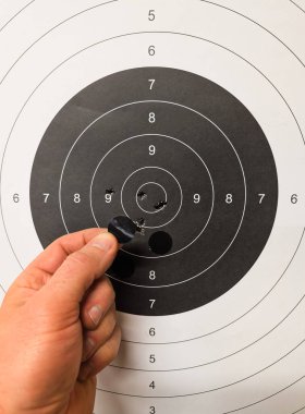 Atış poligonunda, bir adamın eli bir spor hedefindeki kurşun deliklerini çıkartmayla kapatır. Fotoğrafı kapat..