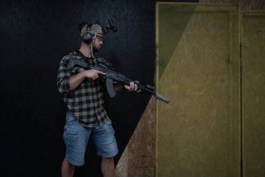 A civilian man practices tactical shooting using a night vision device and a rifle at a shooting range. clipart