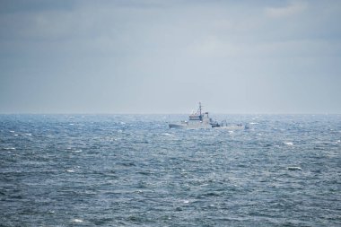 Radarlı ve antenli bir savaş gemisi bulutlu bir gökyüzünün altında Baltık Denizi 'nin genişliğini keser ve dalgalarda köpüklü bir iz bırakır..