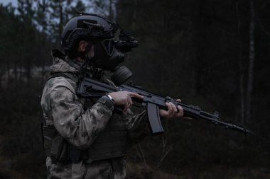 Kıyamet sonrası ormanda gece görüş cihazıyla gaz maskeli bir asker..