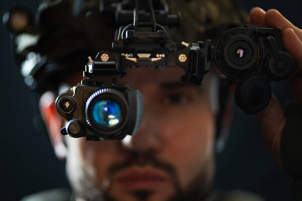 Да, конечно! Вот перевод названия: Военная технология: крупный план солдата с высокотехнологичным прибором ночного видения в паре с тепловизором, установленным на шлеме. Фото с мягким фокусом.