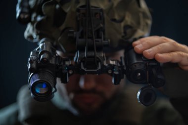 Gece görüş dürbünü olan özel kuvvetler savaşçısı kaskın üzerine monte edilmiş, karanlıkta yumuşak odaklı fotoğraf..