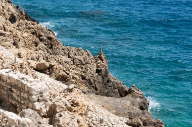 Akdeniz manzaralı kayalık bir kıyı şeridi ve taş cairns ile.