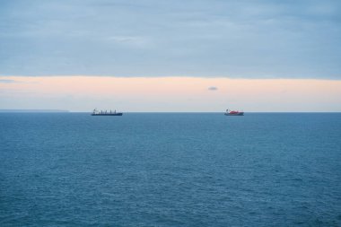 Atlantik Okyanusu, Portekiz 'de ufukta iki kargo gemisi görünüyor. Sakin bir deniz, bulutlu bir gökyüzü ve gün batımını andırıyor..
