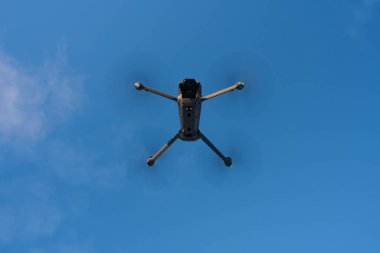 Mavi gökyüzünde kuadkopter dron silueti.