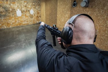 Kel adam atış poligonunda 9mm 'lik bir tüfekle arkadan ateş ediyor..
