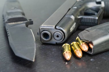 Siyah tabanca, 9 mm 'lik fişekler ve taktik bıçağı, makro fotoğraf..