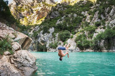 Genç bir adam bir yaz günü Verdon Dağı gölündeki bir uçurumdan atlıyor..