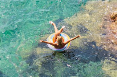 Nice 'de bir yaz günü, açık ve temiz suyla denizde şişme bir yüzükte yüzmekten hoşlanan bir kız..