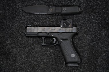 Baltık 22 Mart 2025. Kırmızı nokta görüşlü taktik tabanca Glock 45 Hedef KOA ve İtalyan bıçak oranı.