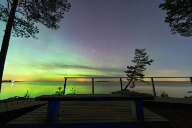 İzleme platformundaki tenha bir bank, Kaberneeme, Estonya 'daki yeşil Aurora Borealis' i ve denizin üzerindeki yıldızları mükemmel bir şekilde görebilmektedir..