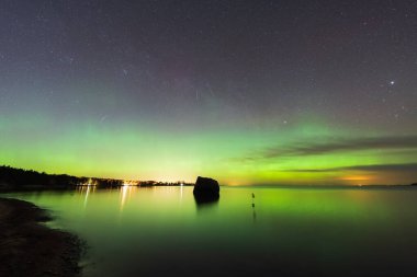 Yeşil Aurora Borealis, Finlandiya Körfezi 'nin sakin sularını yıldızlı bir gökyüzünün altında yansıtır..