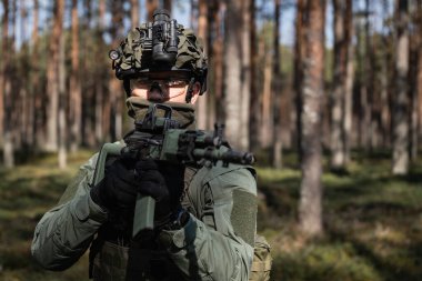 Tam teçhizatlı asker, miğfere takılı gece görüşü taktiksel orman görevi sırasında tüfeği hazır..