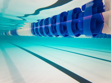 Yüzme havuzu şeridi ayırıcısının su altı görüntüsü berrak mavi su ve taban çizgileri.