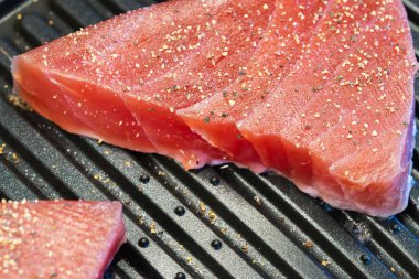 Çiğ, baharatlı Ahi ton balıklı biftekler elektrikli ızgara tavasında pişiyor, kapalı mekanda yakın çekim görüntüsü..