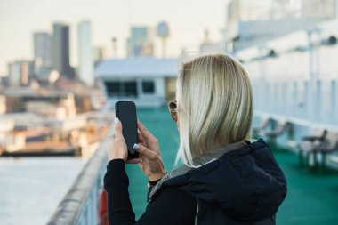 Tallinn 'in panoramasının arkasındaki kadın feribotla şehre yaklaşırken akıllı telefonuyla konuşuyor.. 
