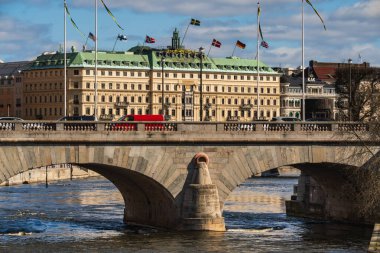 STOCKHOLM, SWEDEN - 4 Nisan 2025: Güneşli bir günde Stockholm şehir merkezindeki tarihi Norrbro köprüsünün ve etrafındaki mimarinin görüntüsü.