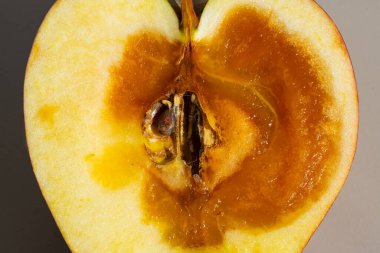 Çürük kahverengi bir çekirdekle ikiye bölünmüş bir elmanın yakın çekimi, iç meyve bozulmasını veya hastalığını gösteriyor..