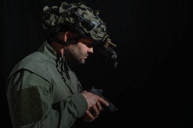 Gece görüş cihazıyla taktik kasklı bir ajan elinde tabanca tutuyor. Karanlıkta harekete geçmeye hazır ya da tehlikeli bir görev..