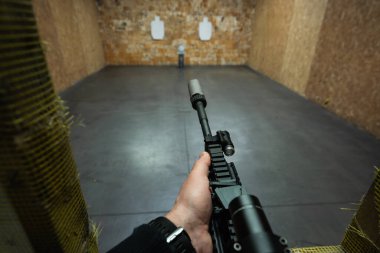 Birinci şahıs bakış açısı: optik görüşlü ve kapalı alandaki hedeflere susturuculu bir taktik tüfeği hedef alan kişi.